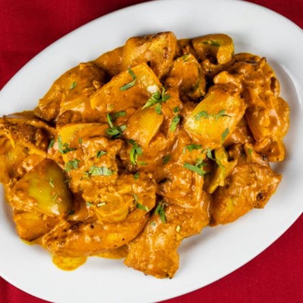 Shri Ganesh's Indian Aloo Gobi, a potato and cauliflower curry, on a white plate.
